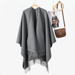 Poncho scialle in maglia grigio scuro a tinta unita con lunghe nappe su sfondo bianco