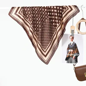 Dettaglio di foulard quadrato in seta con motivi geometrici e pois appeso su un gancio