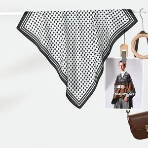 Dettaglio di un foulard in seta con classici pois neri e bordo nero raffinato