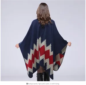 Macro detail of navy blue knitted poncho with red and grey zigzag patterns on the hem