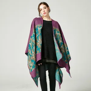 Detail of knitted poncho featuring purple and teal camouflage pattern and fringe edges