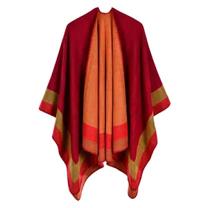 Detail of knit shawl poncho featuring red and orange reversible layers and striped hem