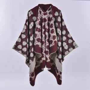 Detail of burgundy knitted shawl showing thick jacquard fabric and white stitched edges