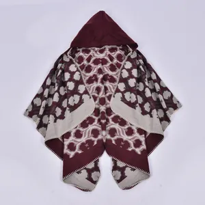 Detailed macro view of knitted poncho showing colorful floral patterns and hem edges