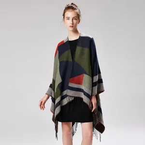 Close-up of geometric color-block knit poncho featuring tassel trim and split hem