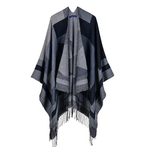 Detail of a navy and gray geometric knit shawl featuring fine fringe and brand neck label