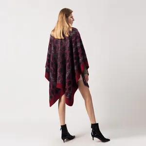 Détail du motif léopard géométrique rouge et bleu sur un poncho en maille épaisse