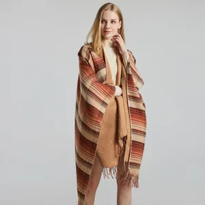 Classic plaid shawl wrap with tassels and striped pattern worn over a beige dress