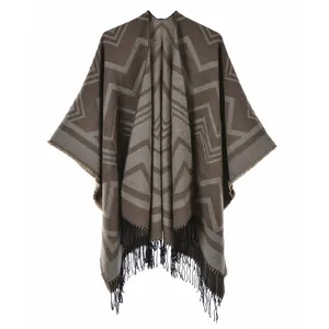 Nahaufnahme von Strick-Poncho mit Erdtönen, geometrischem Muster und Fransensaum