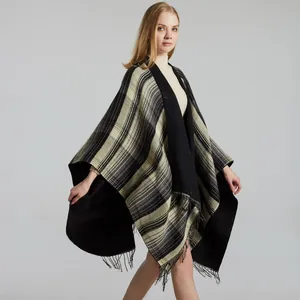 Classic black and white checkered poncho wrap with fringe trim over cream turtleneck