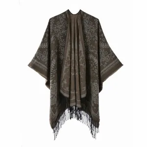 Detail of bohemian paisley knit shawl featuring decorative black tassels and soft fabric