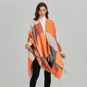 Detail of knit color-block poncho featuring orange and beige plaid with long tassels