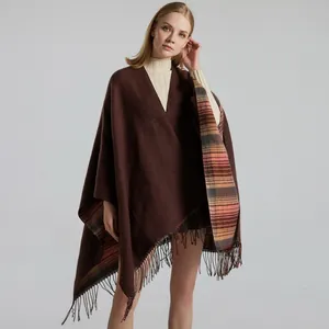 Close-up of thick brown knit shawl with warm plaid lining and fine tassel details