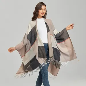 Detail of color-block knit poncho with grey and beige patterns and fringe trim