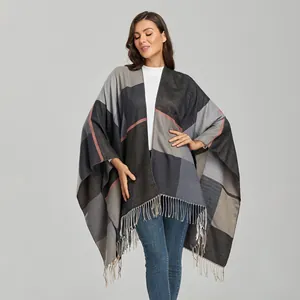 Detail of oversized color block poncho with soft geometric patterns and long tassel fringe