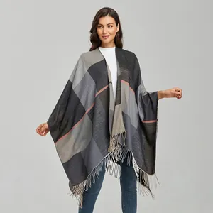 Detail of plaid shawl cape featuring grey and beige color block pattern with tassel edges