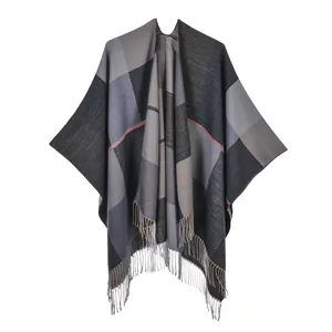 Detail of plaid poncho shawl featuring fringe trim and warm jacquard woven texture