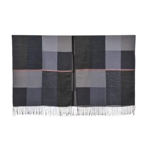 Close-up of thick grey checkered knit shawl with fringe tassels and pink stripe detail