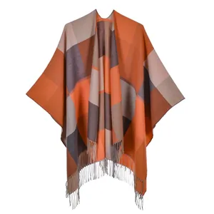Close-up of orange and grey checkered poncho wrap featuring decorative long tassels