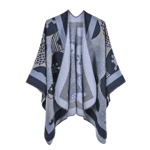 Close-up of knit shawl poncho featuring geometric stripes and blue floral patterns