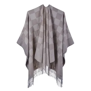 Detail of grey and beige checkered knit poncho cape featuring soft fringe tassels