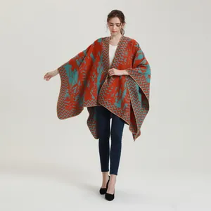 Detail of knitted poncho featuring orange and teal contrast abstract map patterns
