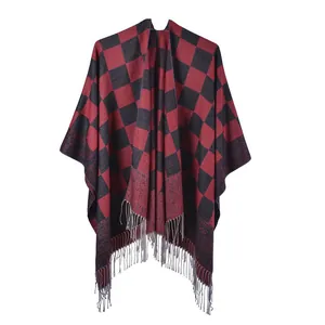 Detail of red and black buffalo plaid poncho featuring long tassel fringe edges