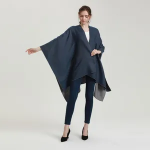Navy blue and grey reversible cape shawl wrap worn over a white top and blue jeans