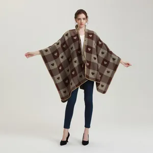 Detail eines karierten Damen-Ponchos mit braunen Herzmustern und Fransenkanten