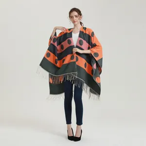 Close-up of thick knit color-block shawl featuring grey fringe detail and geometric patterns