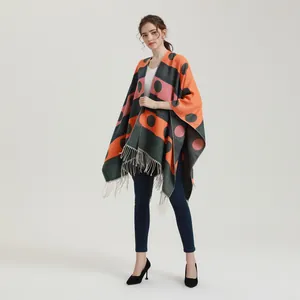 Macro detail of knitted cape shawl with geometric contrast patterns and long fringe edges