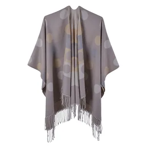 Detail of soft taupe knitted shawl featuring large beige polka dots and fine tassel fringe