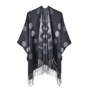 Detail of gray polka dot poncho featuring fringe trim and soft knitted cashmere-like texture