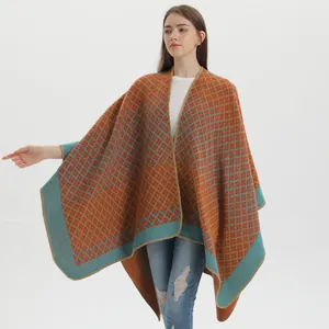 Detailed close-up of thick knitted poncho featuring orange and blue geometric plaid patterns