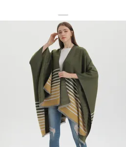 Détail d'un châle tricoté vert foncé avec rayures jaunes blanches et pompons