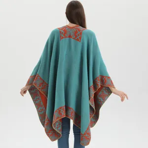 Detail view of ethnic blue knit poncho featuring orange snowflake geometric patterns