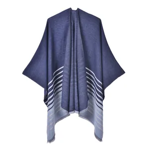 Détail d'un châle tricoté en dégradé bleu avec rayures blanches et finitions à franges