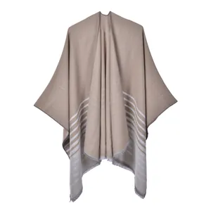 Détail du châle en tricot beige montrant des rayures blanches et un ourlet à franges