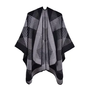 Détail du poncho en tricot montrant des motifs géométriques gris et une texture douce
