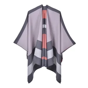 Detailed close-up of striped knit poncho featuring soft pink, grey and orange patterns