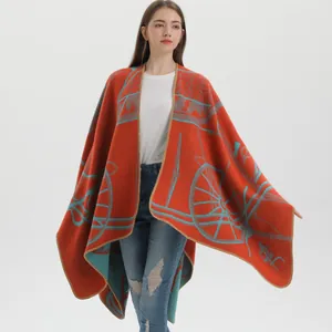 Detail of knit poncho wrap showing thick orange fabric with vintage carriage wheel pattern