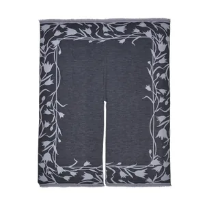 Detail of grey knitted shawl showing grey tulip floral patterns and fine fringe trim