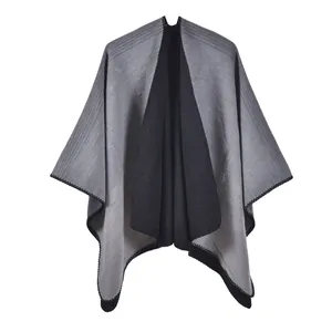 Close-up of dual-tone knit poncho showing grey and black fabric texture and stitched edges