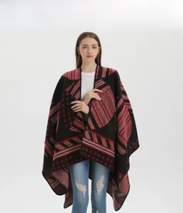 Dettaglio di un poncho in maglia rosso e nero con motivi geometrici e caduta morbida