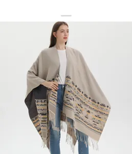 Detail of beige knit shawl with geometric ethnic patterns and delicate fringe trim