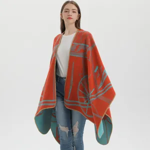 Knit shawl poncho with abstract patterns in brick red and blue for autumn and winter