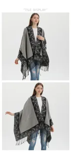 Flat lay display of a grey knit poncho with black floral patterns and tassel edges