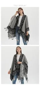 Detailed view of grey knit shawl with black floral patterns and dense fringe tassels