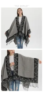Detail of grey knitted poncho featuring vintage floral patterns and long fringe edges