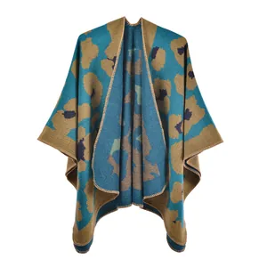 Detailed knit texture of a blue leopard print poncho wrap with brown stitched edges